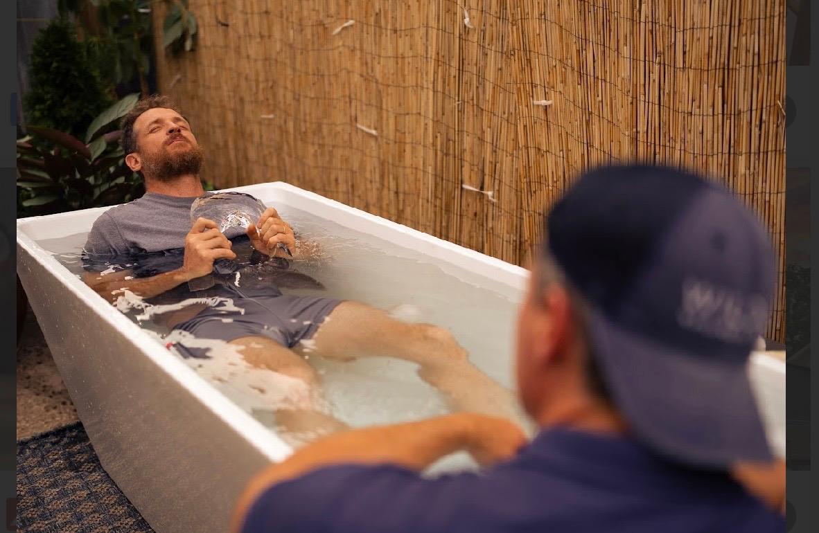 A participant lying calm in the cold plunge tub holding a piece of ice